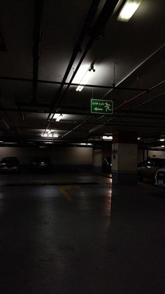 an empty parking garage with cars parked in the lot and lights on at night time