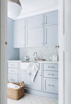 a white kitchen with lots of cabinets and a basket on the floor in front of it