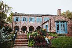 an old brick house with blue shutters and flowers