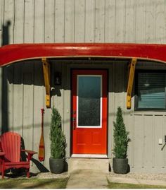 a red surfboard sitting on the side of a building next to a red door