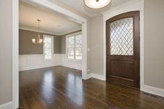 an empty room with hard wood floors and white trim on the walls, windows, and doors