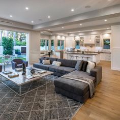 a living room filled with furniture next to a kitchen and dining room table in front of a large window