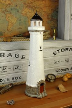 a small white lighthouse sitting on top of a wooden table next to other items in front of a map