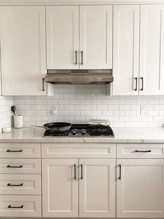 a kitchen with white cabinets and black stove top