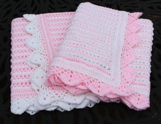 two pink and white crocheted blankets sitting on top of a black table next to each other