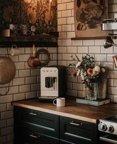 a coffee maker sitting on top of a wooden counter next to a vase with flowers