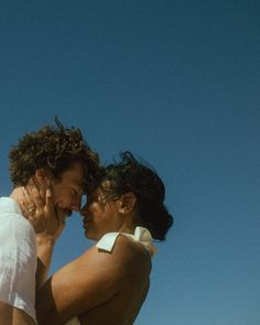 two people standing next to each other under a blue sky with one holding the other's head