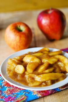 apples and bananas are sitting on a table next to the plate with some kind of food in it