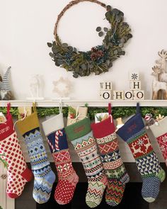 christmas stockings hanging from a mantel in front of a wreath