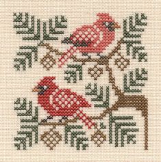 a cross stitch pattern with two red birds on a tree branch and one brown deer