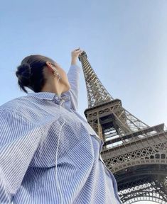 a woman standing in front of the eiffel tower looking up into the sky