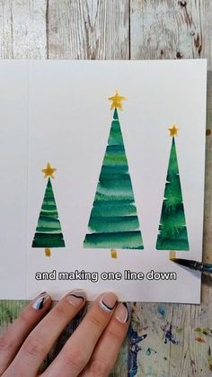 someone is holding up some christmas cards with trees on them and the words, and making one line down