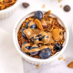 two bowls filled with granola and blueberries on top of a white tablecloth