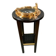 a black and gold side table with a glass bowl on it's stand,