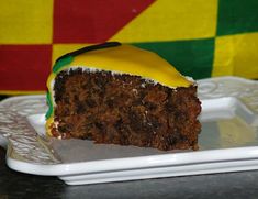 a piece of cake on a white plate with yellow frosting and green icing