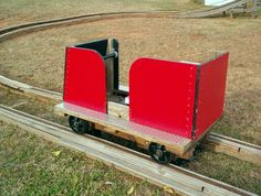 a small red train cart sitting on top of a wooden track