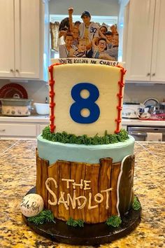 a birthday cake with the number eight on it and people in baseball gear sitting on top