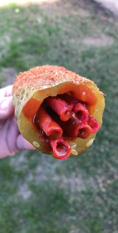 a person holding up a half eaten hot dog bun with ketchup on it