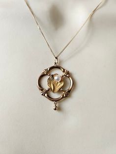 An absolutely glorious vintage necklace.  Hallmarked 9ct gold.  Art Nouveau in style, dating to around the 1960s. Delicate, exquisite details, with a sweet dangling ball drop. Reminds me of the birth of Venus, or something that would adorn a mermaid.  All solid 9ct gold. The pearl is a faux pearl. I am happy to replace with a genuine freshwater pearl if you prefer.  Chain: 16 inches Pendant: a little over 2cm wide  Rare & special ~ Vintage Jewelry With Pearl Charm Round Pendant, Gold Art Deco Necklace With Pearl Pendant, Art Deco Pearl Pendant Jewelry, Antique Pearl Pendant Necklace, Vintage Pearl Charm Jewelry For Anniversary, Vintage Yellow Gold Pearl Pendant Necklace, Vintage Gold Round Pearl Necklace, Vintage Jewelry With Pearl Charm For Anniversary, Art Deco Pearl Pendant Necklace As Gift