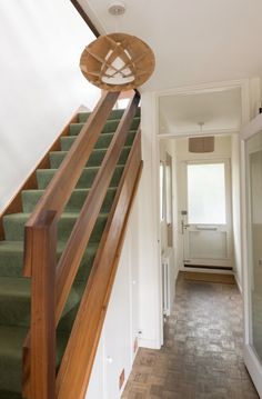 the stairs are made of wood and have green carpeted treads that lead up to the second floor