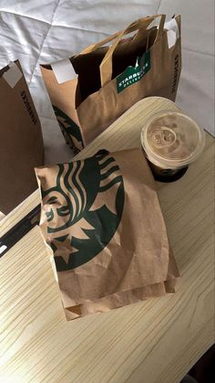 there is a starbucks bag on the table next to a cup of coffee and some paper bags