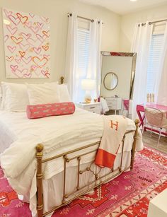 a white bed with pink and orange pillows on top of it next to a mirror