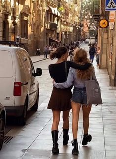 two women walking down the street with their backs to each other and one holding her arm around another woman's shoulder