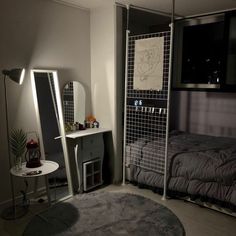 a bedroom with a bed, desk and mirror in it's corner next to a night stand