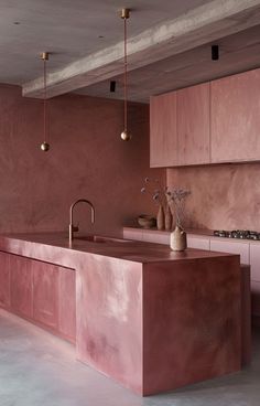 a kitchen with pink walls and counters in the center, along with two vases on the counter