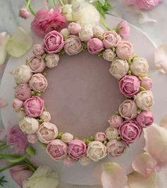 a cake decorated with pink and white flowers on top of a plate, surrounded by petals