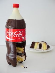 a bottle of coca cola sitting next to a piece of cake