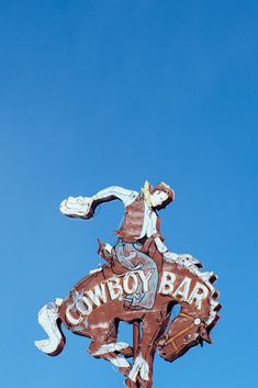 a sign that is on the side of a building with a cowboy bar painted on it