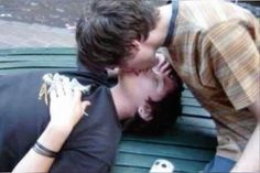 two people kissing each other while sitting on a bench