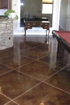 a pool table in the middle of a living room with tile flooring and wood cabinets