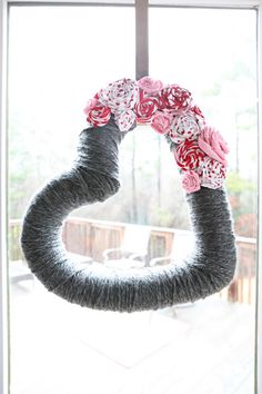 a wreath made out of yarn and flowers on a window sill in front of a sliding glass door