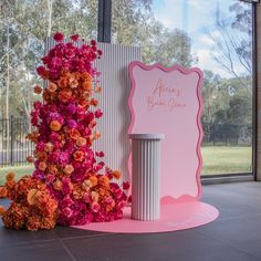 pink and orange flowers are on display in front of a sign