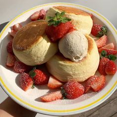 a white plate topped with rolls covered in powdered sugar and strawberries