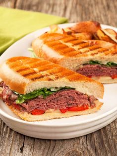 a sandwich cut in half sitting on top of a white plate next to a green napkin