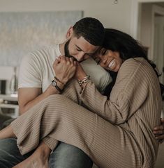 a man and woman hugging each other while sitting on a couch in a living room