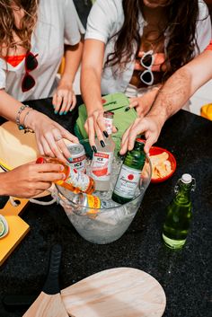 several people are making drinks in a bucket