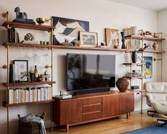 a living room filled with furniture and a flat screen tv on top of a wooden shelf