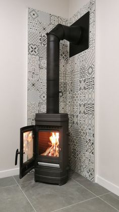 a small stove in the corner of a room next to a wall with tiles on it