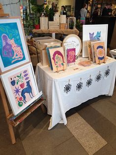 several paintings are displayed on a table in a store