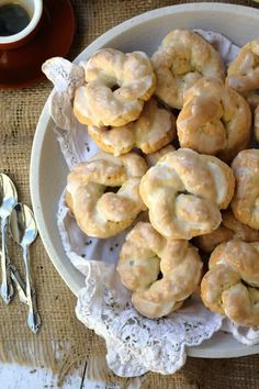 a white plate topped with donuts on top of a doily next to a cup of coffee