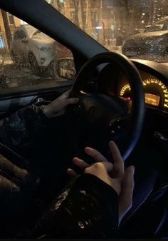 a person driving in the rain with their hand on the steering wheel