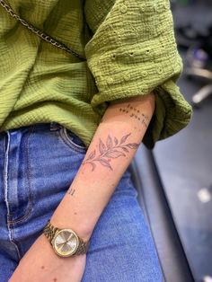 a woman with a tattoo on her arm and wrist is sitting in front of a chair