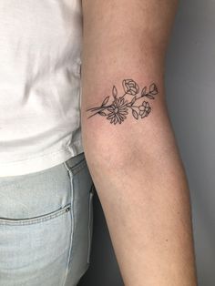 a woman's arm with a small flower tattoo on the left side of her right arm