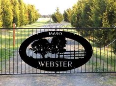 a gate with a sign that says webster on it and trees in the distance behind it