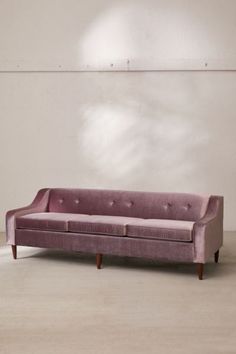 a pink couch sitting in front of a white wall