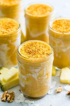 four jars filled with food sitting on top of a white counter next to sliced pineapples